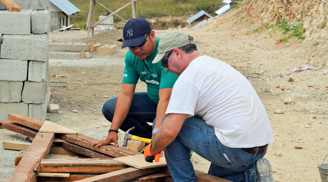 En un proyecto de ayuda en desastres, un miembro del personal orienta a un voluntario. Voluntario de Projects Abroad y personal local reconstruyendo una escuela como parte de la ayuda humanitaria.